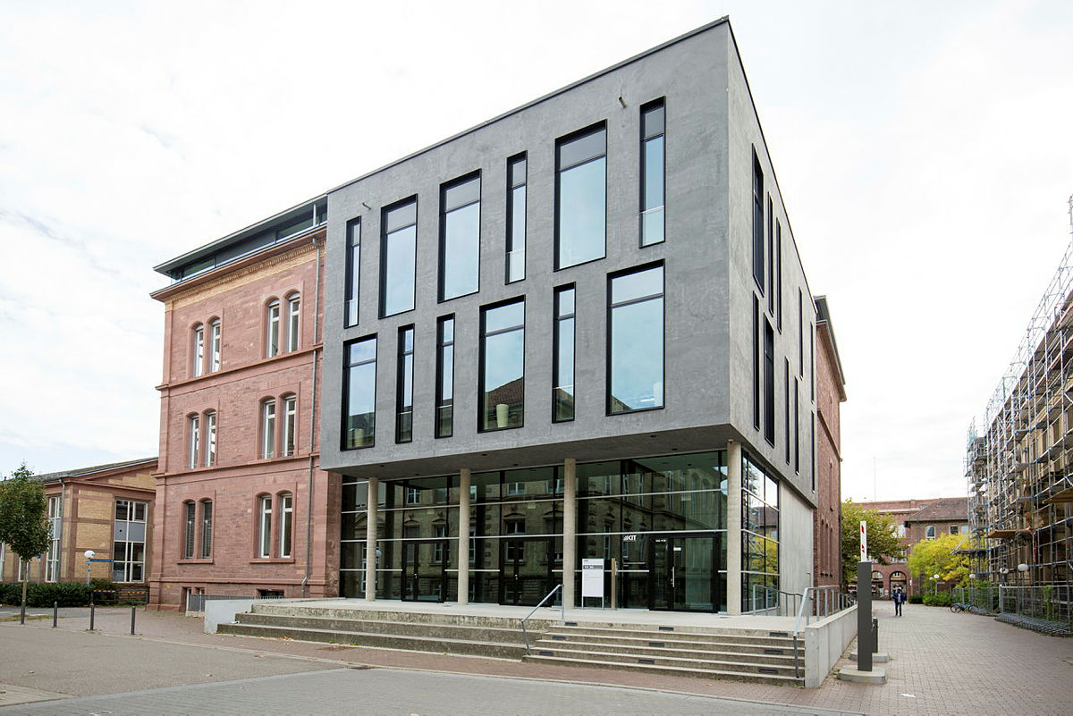 Neues, modernes Büro- oder Hochschulgebäude aus Glas und Beton neben traditionellem roten Backstein.